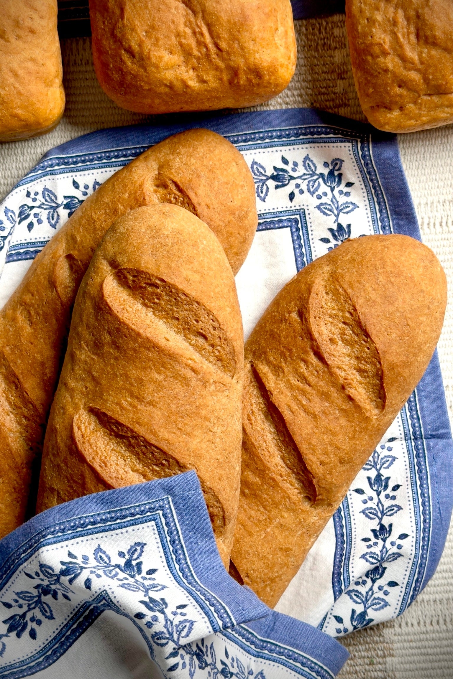 Two loaves of gluten free french bread on a blue and white patterned cloth